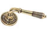 From The Anvil Reeded Door Handles On Round Rose, Aged Brass - 33087 (sold in pairs)